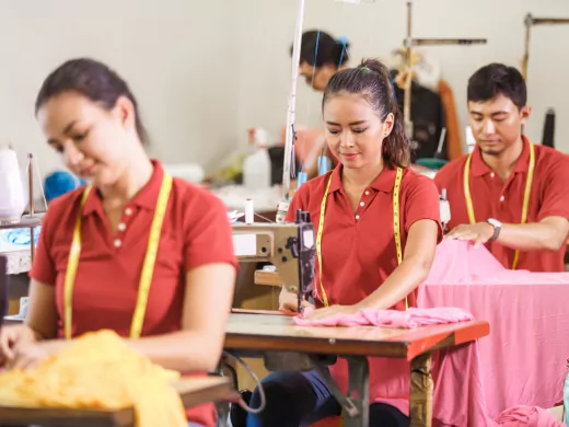 asian workers in garment factory sewing with industrial sewing machine