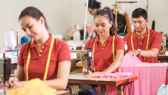 asian workers in garment factory sewing with industrial sewing machine
